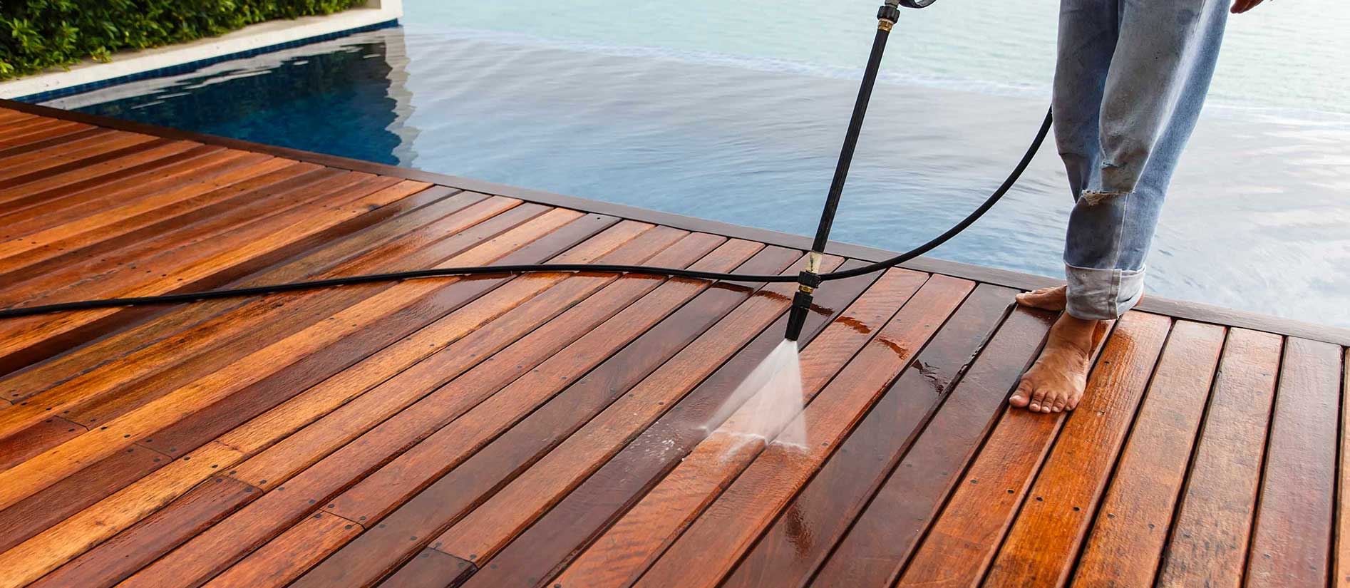 Professional pressure washing a wood deck beside a pool — Vero Beach, FL